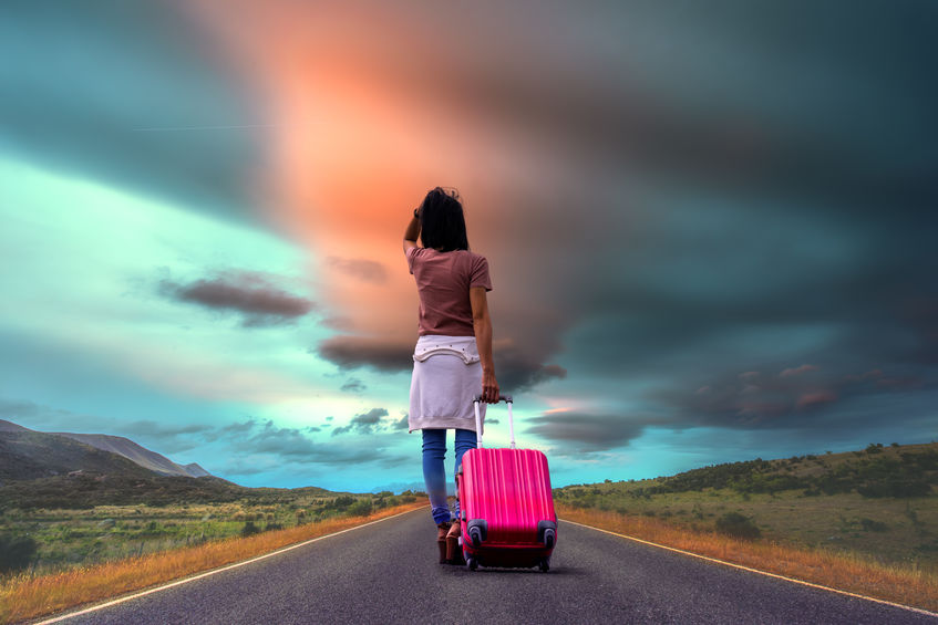 young girl walking down road with suitcase