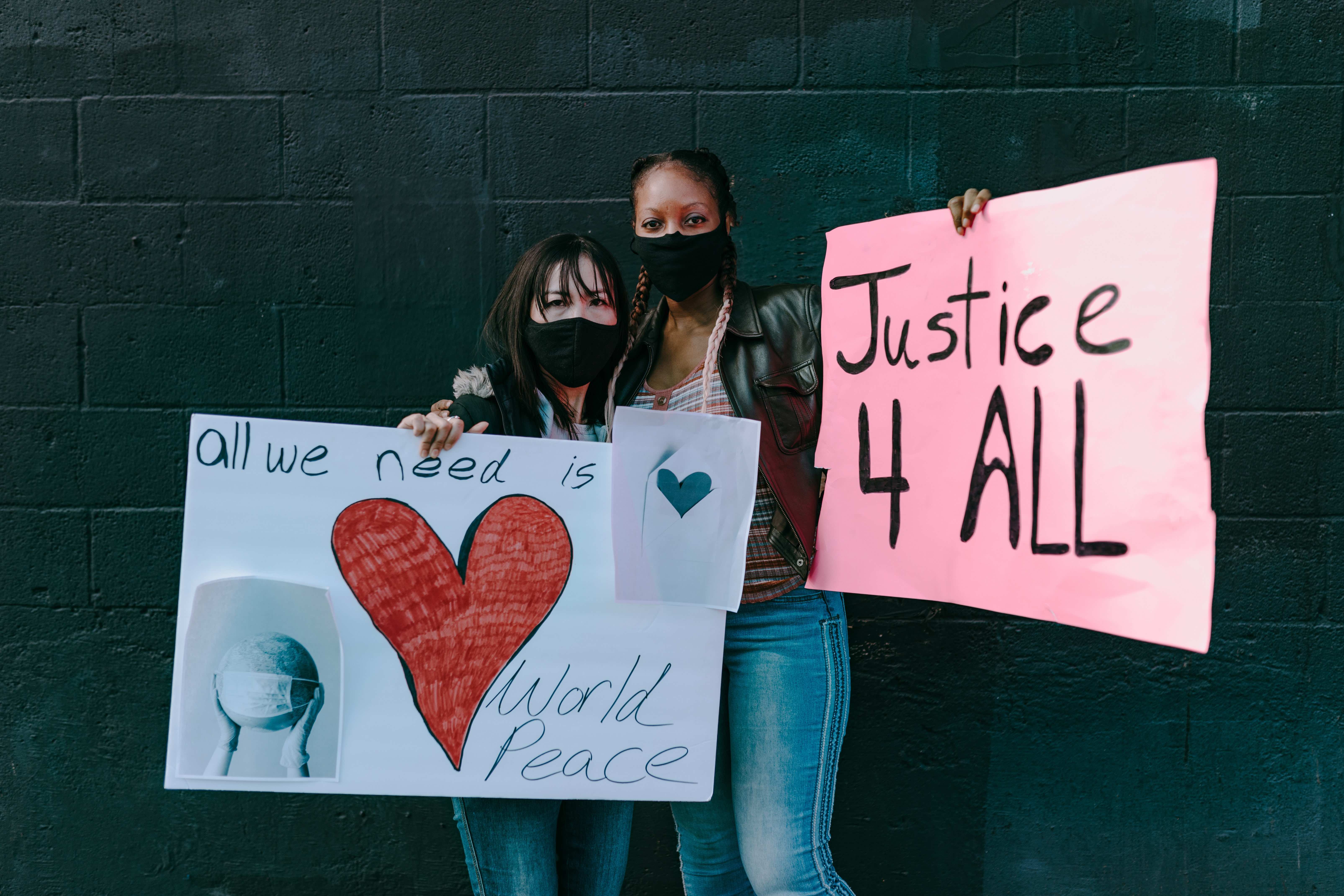 Two Women in Masks Holding Signs