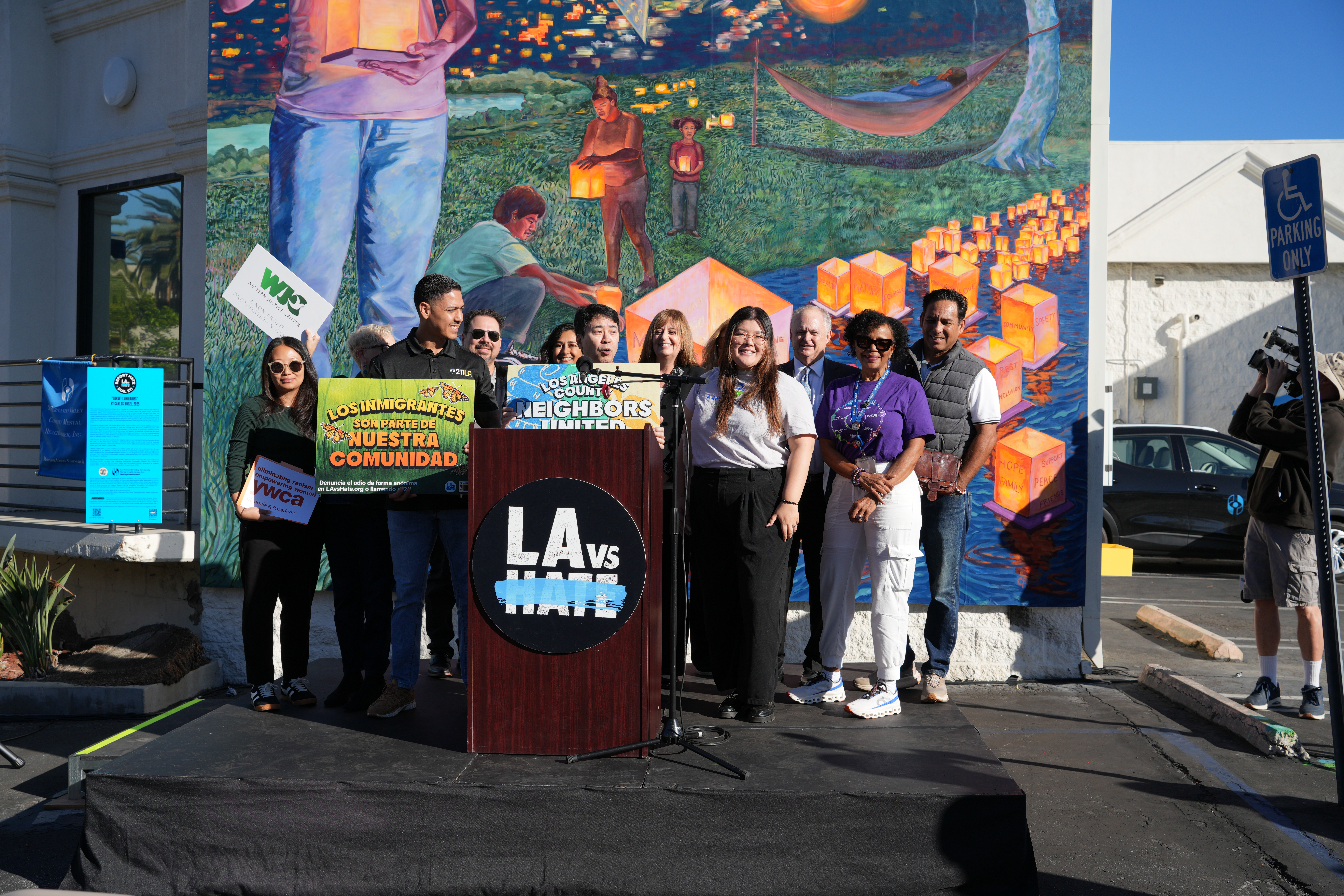 LA vs Hate podium, with Manager Anthony Perez from LA vs Hate on the Left holding green sign