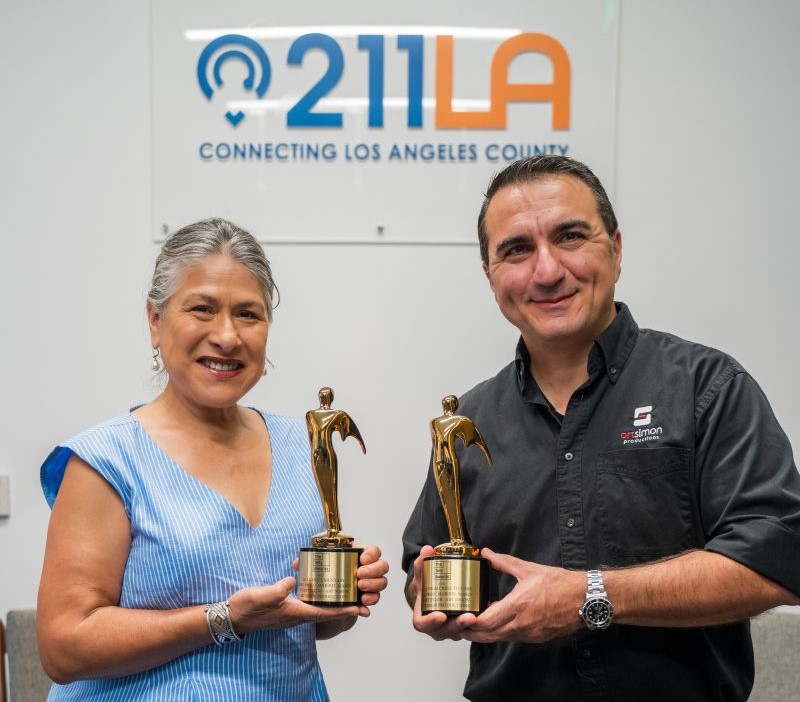 Maribel Marin on the left, wearing blue shirt and white pants. Art Simon on the right wearing black button up and black pants