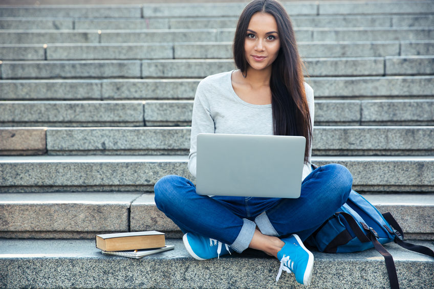 young woman sitting on stair steps using her computer
