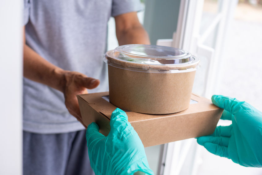 gloved hands delivering food to customer at home