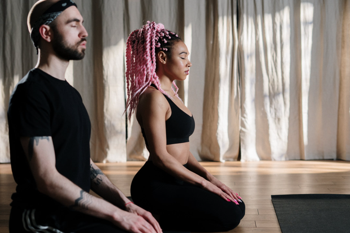 Two Individuals Sitting on Floor Meditating 