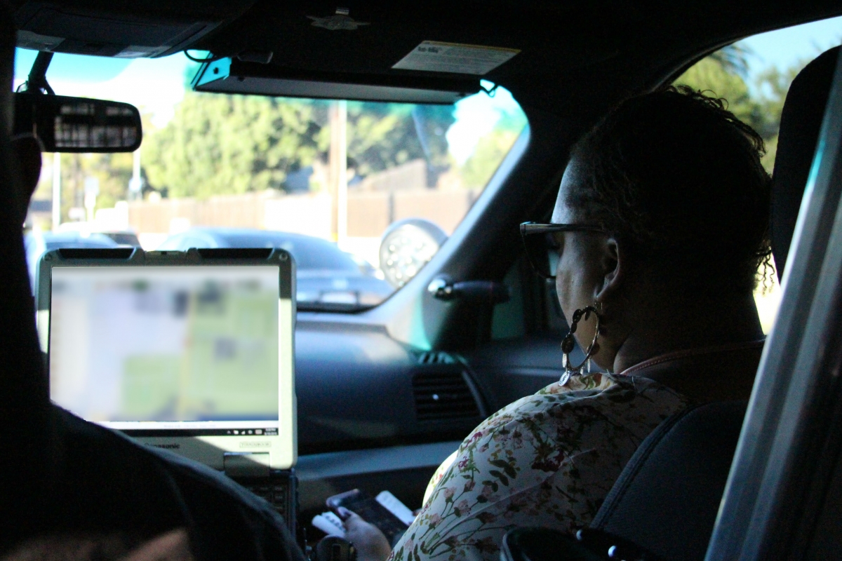 Tina Webb checks her notes while Deputy Miranda makes his way through traffic.]