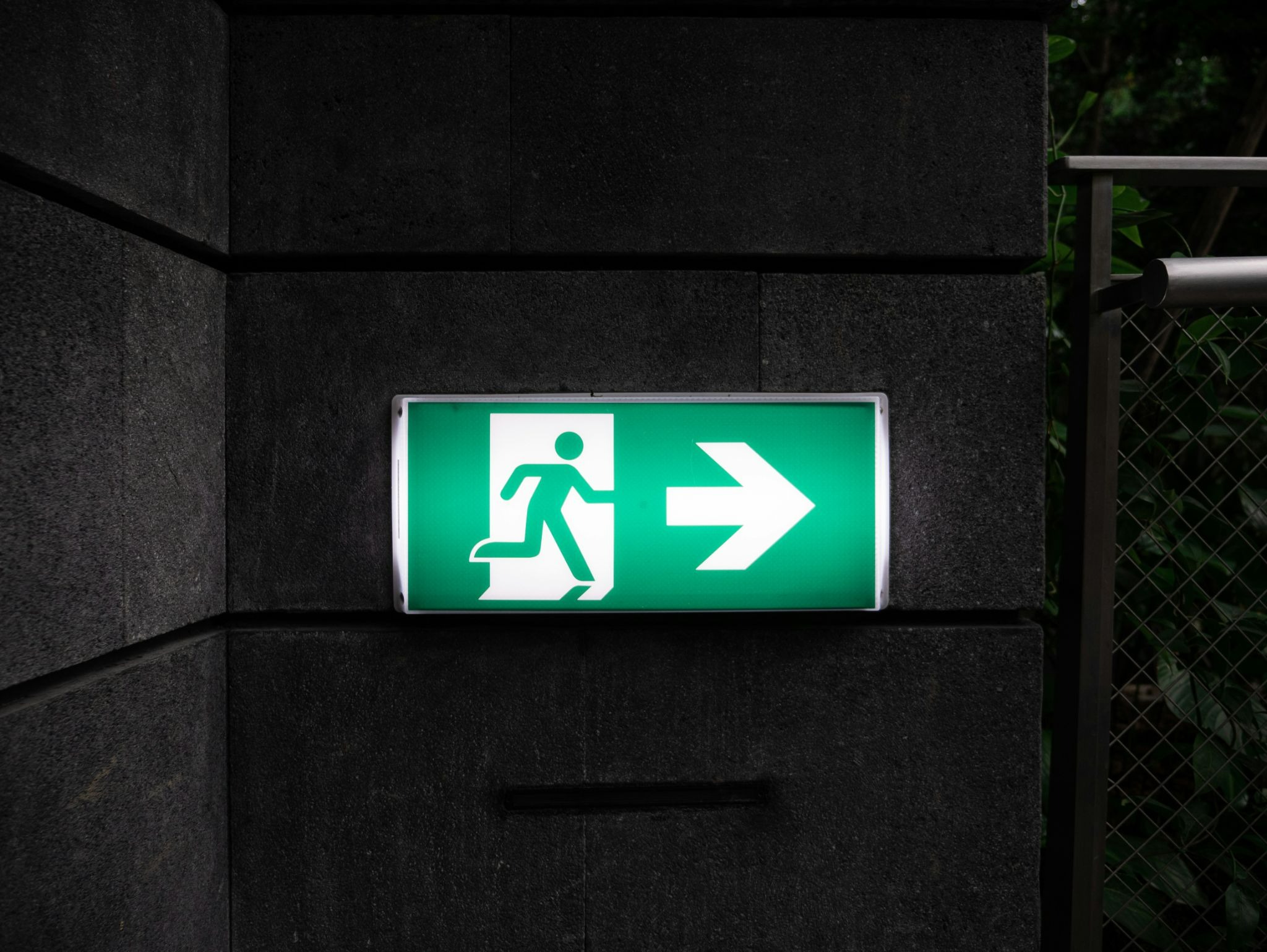 emergency exit sign pointing to the right hanging on a wall