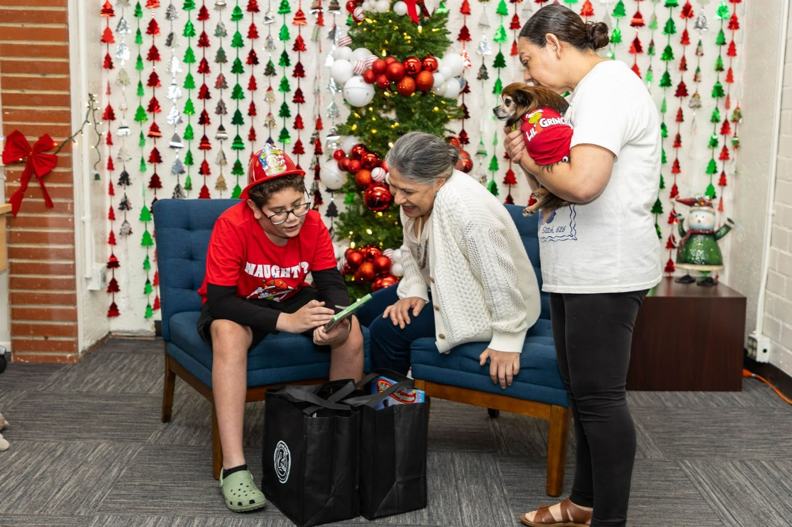 Maribel Marin opens gifts with a wildfire-impacted family around the Christmas tree. Which includes a Child, Mother, and pet dog.