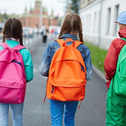 Elementary school kids with bright colored backpacks walking to school