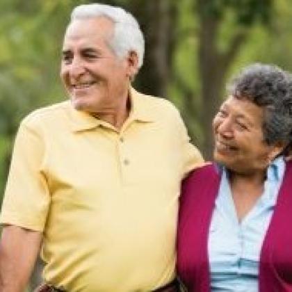 latina caregiver walking in park with elderly couple