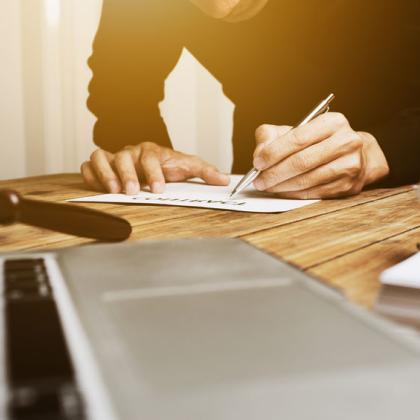 man filling out application laptop and gavel on the foreground