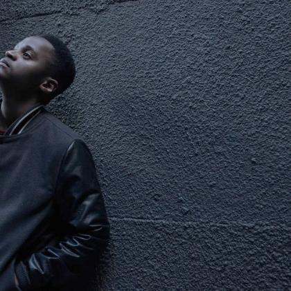 Black youth leaned against wall looking up