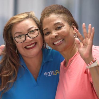 Care Coordinator left hand side, Yvonne wearing glasses and blue 211 LA shirt, Robin Ivory on the right, smiling and waving wearing a pink shirt
