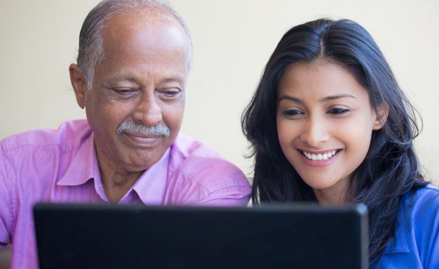 Elderly man and daughter working on laptop together