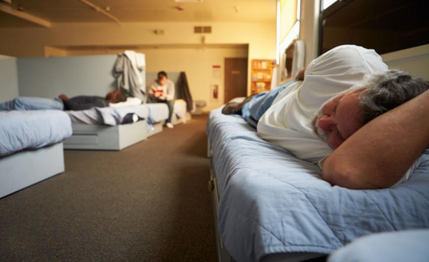Man resting on bed in homeless shelter