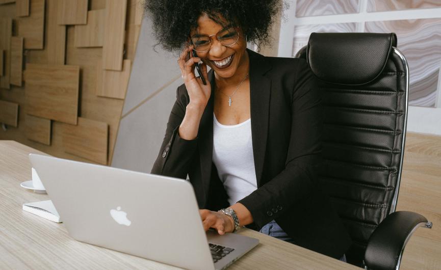 Women On Phone and Labtop Sitting at Desk