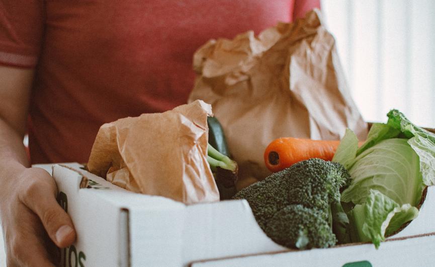 Individual holding box full of groceries
