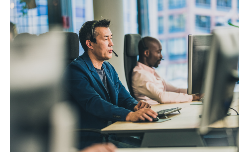 Two people talking on the phone wearing a headset while using the computer