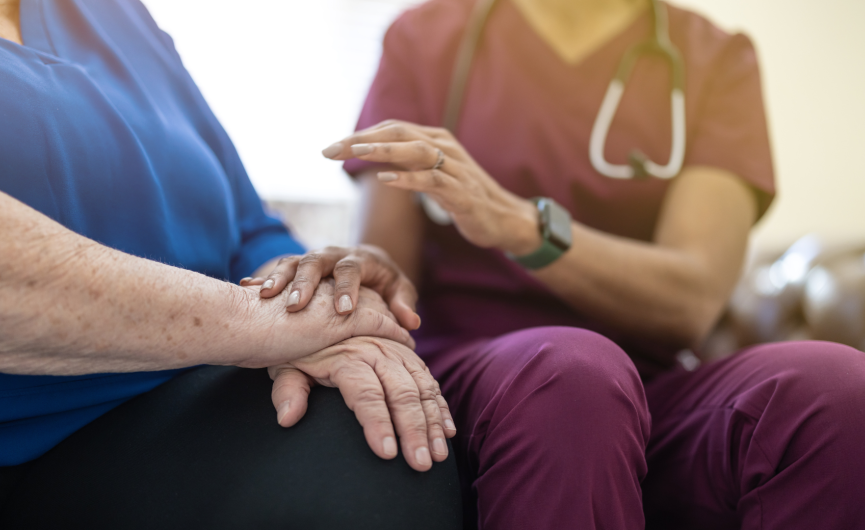 Health professional putting hands on top of clients hands while sitting down, sympathetic feeling
