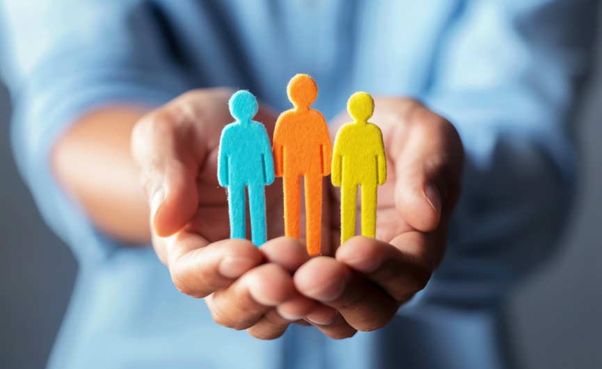Person wearing a blue long sleeve shirt, has hands out while cut out figures standing in between the persons hands