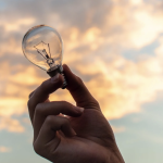 Light Bulb Held In Hand Facing Sky